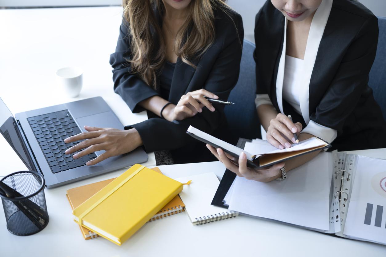 Två kvinnor på kontor vid dator och anteckningbok